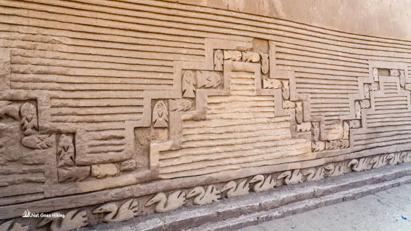 Adobe wall at Chan Chan with stepped geometric friezes, rows of fish, and a lower band of pelicans