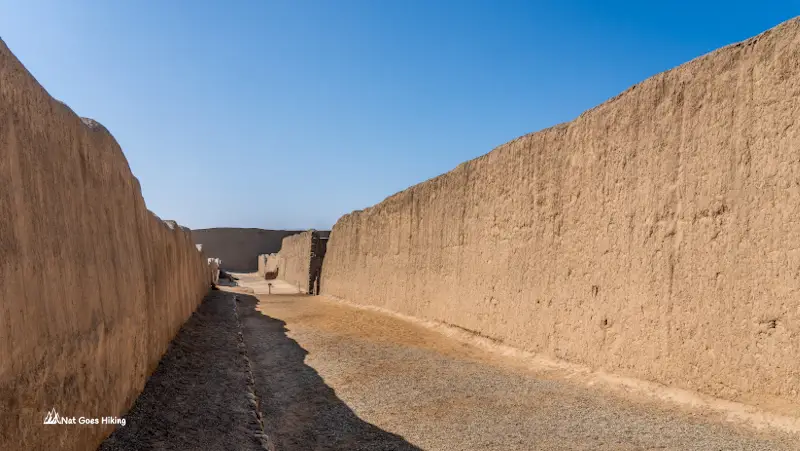 Walkway leading between tall eroded adobe walls at Chan Chan