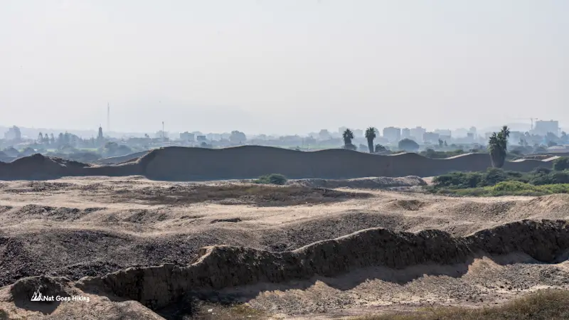 Eroded adobe walls of Chan Chan with the city of Trujillo visible in the background