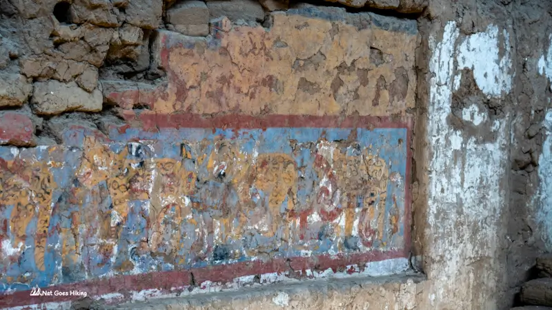 Faded blue-background frieze at Huaca de la Luna with yellow, black-spotted jaguar figures, Peru