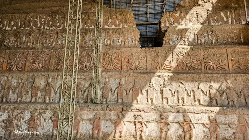 Section of Huaca de la Luna's north façade showing tiered Moche reliefs with warrior and dancer figures, Peru
