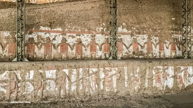 Mural at Huaca de la Luna of figures holding hands above a row of armed marchers, Peru